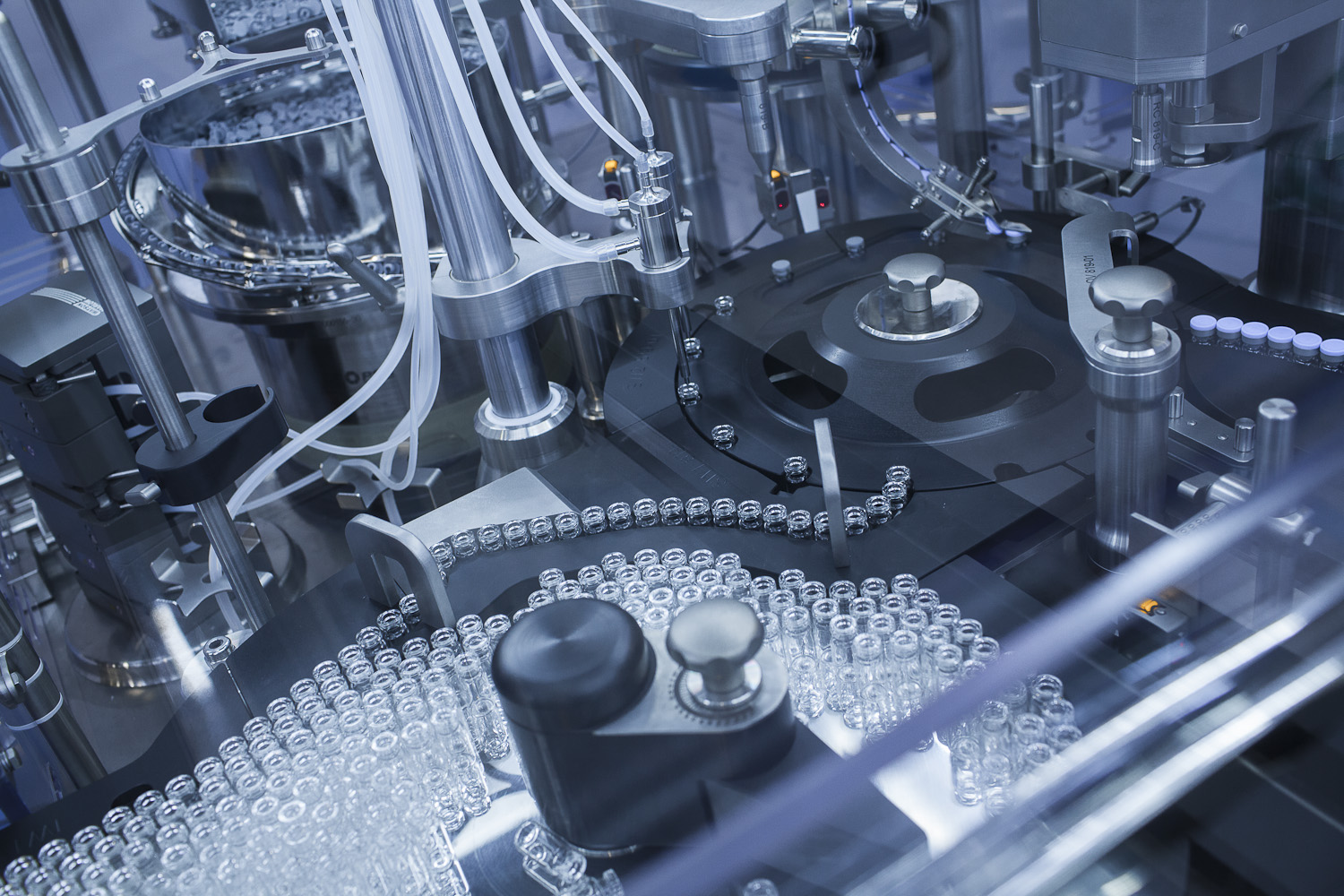 A manufacturing conveyor belt with dozens on clear vials.