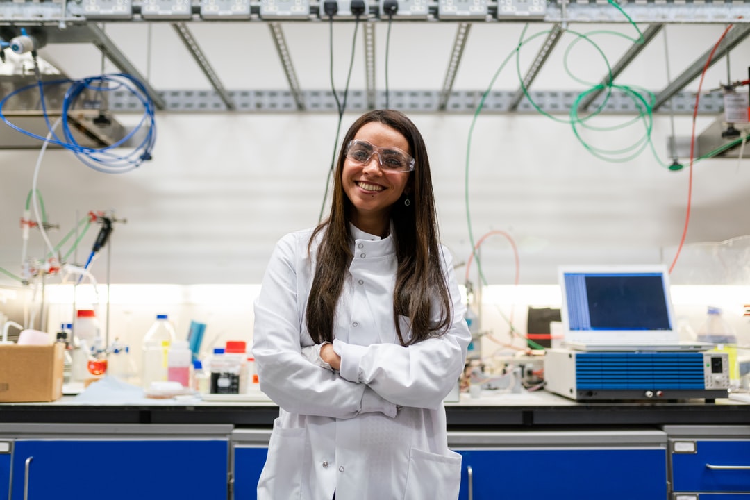 A scientist smiling in front of a lab bench.