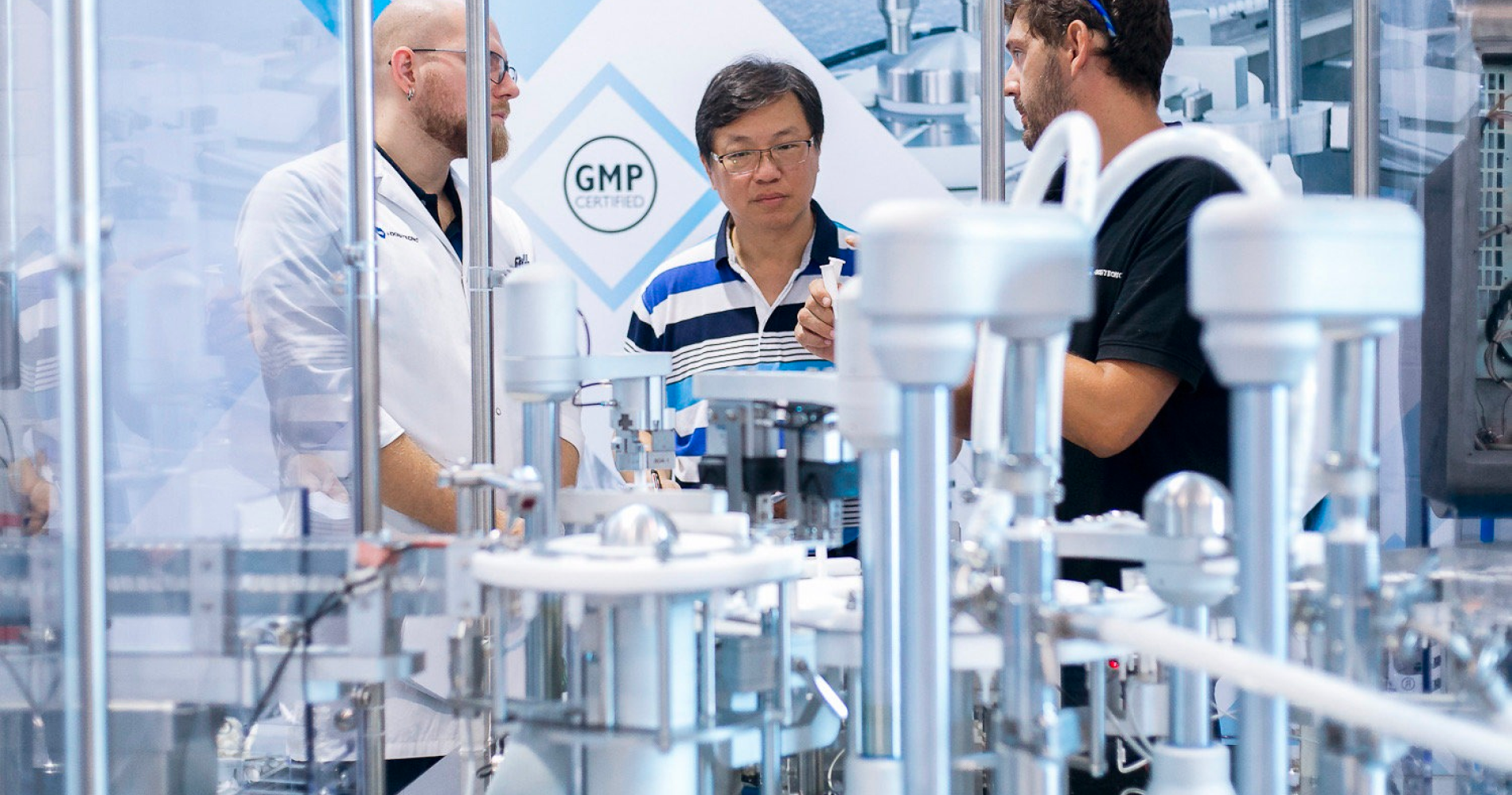 brands Three men having a discussion in a lab.